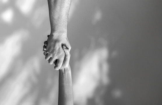 Hands help, vertical, sky. Helping hand outstretched, salvation. Close up help hand. Two hands, helping arm friend, teamwork Copy space. Black and white