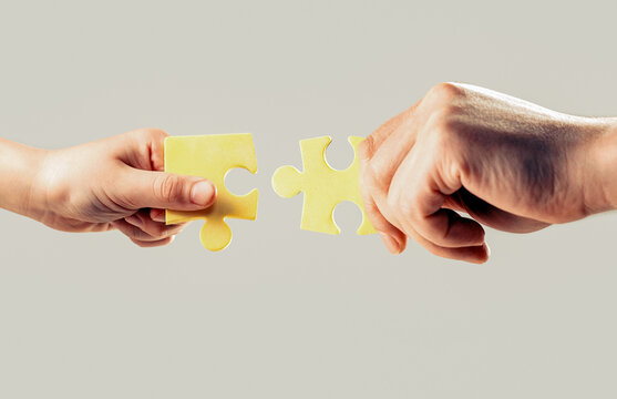 Men and child hands connecting puzzles. Close up hands holding trying to connect couple jigsaw puzzle pieces