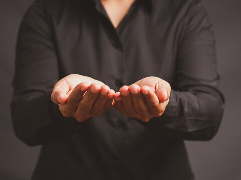 Person Holding Both Open Palms Forward Against Dark Background