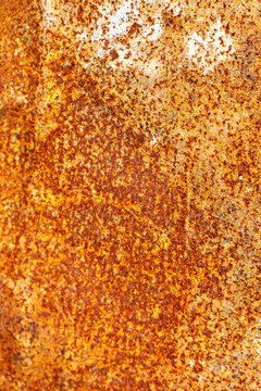 Abstract vertical background texture of weathered orange rusty metal sheet with aged corrosion pattern.