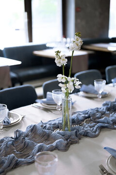 White matthiola flowers in a glass bottle vase on a restaurant table