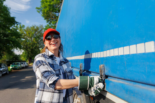 Portrait young adult smiling woman truck driver secures cargo tarp trailer truck  cargo vehicle. Female person girl professional job career working driving freight engine lorry. Logistics industry