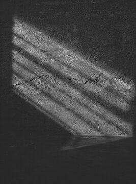 Abstract black and white shadow lines on a textured concrete wall.