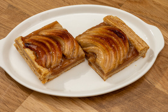 Normandy artisan bakery apple tart with thinly sliced, caramelized apples on buttery puff pastry with glossy glaze; sweet, French breakfast in bakery
