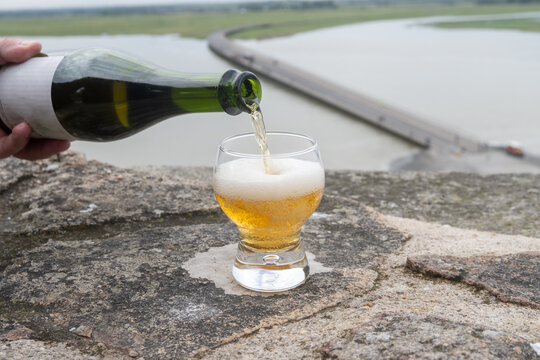 Normandy cider poured on fortress walls of Mont-Saint-Michel stunning abbey hill in ocean, sparkling apple beverage, refreshing taste. France