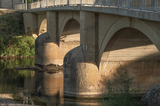 Dreiviertelansicht Neckarbr&uuml;cke Rundbogenbr&uuml;cke aus Sandstein mit halbrunden Str&ouml;mungsteilern mit Spiegelung und Seitenlicht von tiefstehender Sonne in Neckartenzlingen.	
