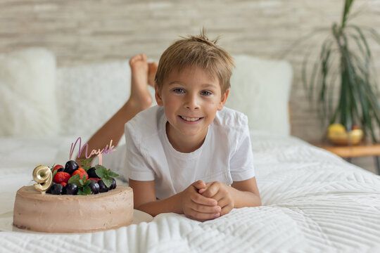 Cute preschool boy with birthday cake with candles at home, preparing for party with friends and siblings