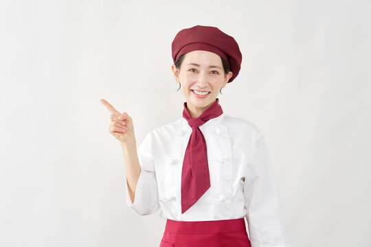 左側を指差すパティシエ女性