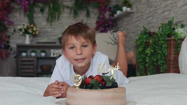 Cute preschool boy with birthday cake with candles at home, preparing for party with friends and siblings