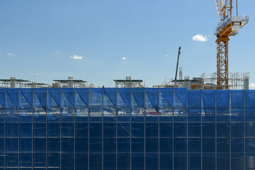 Construction site blue safety net crane scaffolding building urban development architecture industrial daytime. Modern construction site with blue safety netting crane and scaffolding clear sky © pirom
