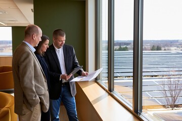 Fototapeta premium Facility managers reviewing commercial building energy costs and planning efficiency upgrades to reduce operating expenses and carbon emissions