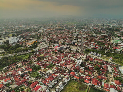 Aerial view of the dense urban landscape with its characteristic red-tiled rooftops, winding streets, and surrounding greenery in Purwokerto, Central Java, Indonesia.