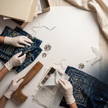 Hands engaged in textile repair and crafting with fabric and tools laid out