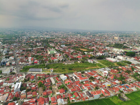 Aerial view of the dense urban landscape of Purwokerto with its characteristic red-tiled rooftops, winding roads, and patches of green vegetation in Purwokerto, Central Java, Indonesia.