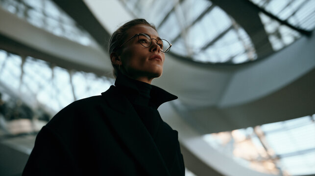 futuristic portrait of stylish person in modern architectural interior, elegant blonde model in black turtleneck against curved white architecture, sophisticated portrait with futuristic architecture