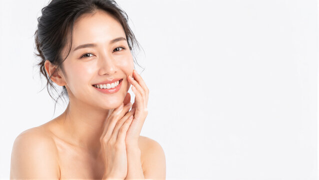 Beautiful young Asian woman with healthy glowing skin smiling and touching face on white background, skincare and beauty concept with copy space