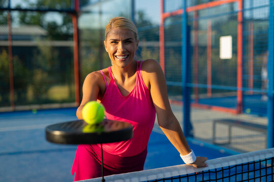 Woman smiling playing padel tennis on court