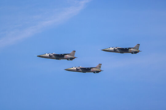 Three military fighter jets flying in a coordinated formation across a clear blue sky, showcasing power, precision, and defense aviation capabilities during an air show display.