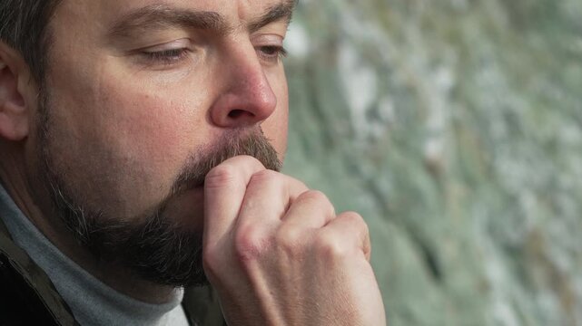 Man eating chocolate middle aged bearded man bites into a piece of milk chocolate outdoors while enjoying a snack break
