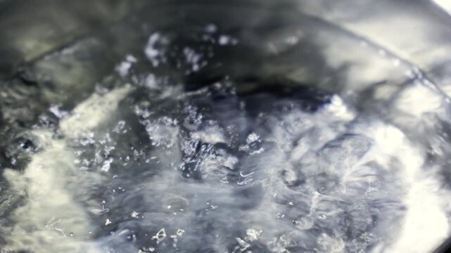 ステンレス鍋の中で激しく泡を立てて沸騰するお湯のクローズアップ映像素材（料理・調理シーン用）