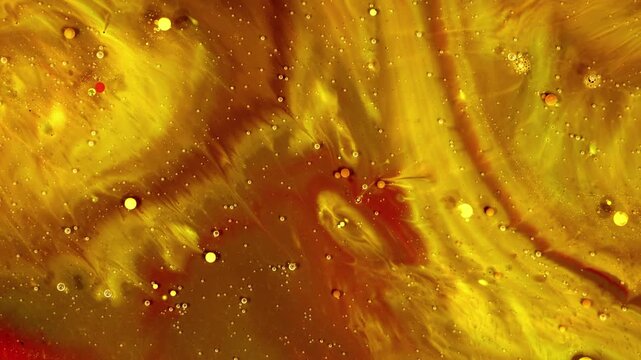 Small bubbles and droplets are visible, floating and moving with the swirling currents and fibrous patterns that resemble organic structures or golden plumes.
