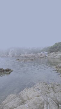 Foggy coastal landscape with calm sea and rocky shore