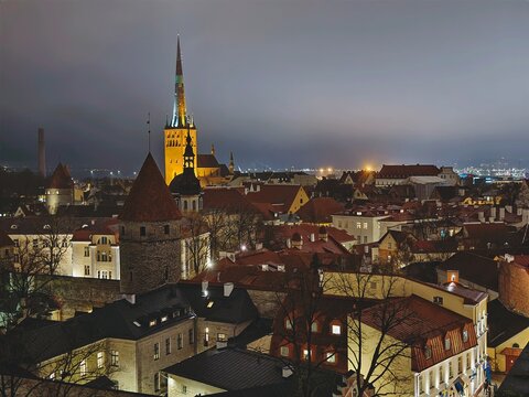 High angle view of Tallinn Old Town skyline at night, illuminated spire of St Olaf Church and medieval towers.