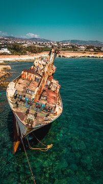 Close up aerial view of the bow of a stranded rusty cargo shipwreck.