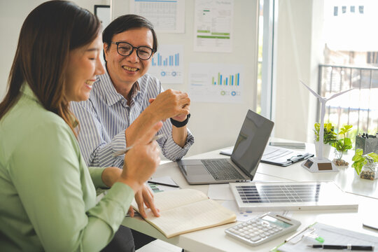 A diverse group of business professionals working together in a modern office, analyzing environmental data and charts to develop eco-friendly, sustainable corporate strategies.