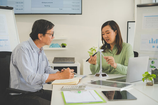 A diverse group of business professionals working together in a modern office, analyzing environmental data and charts to develop eco-friendly, sustainable corporate strategies.