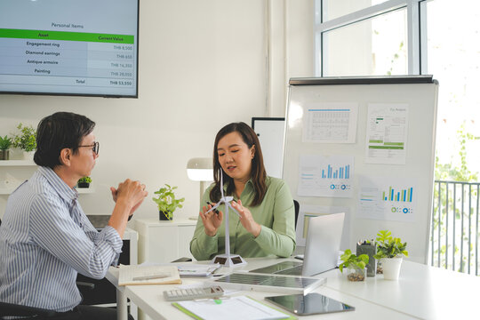A diverse group of business professionals working together in a modern office, analyzing environmental data and charts to develop eco-friendly, sustainable corporate strategies.