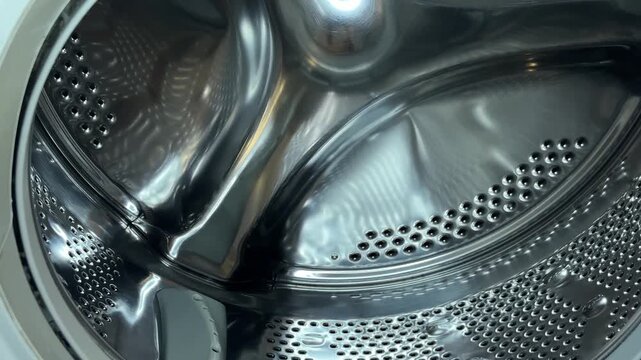 Washing machine empty inside, open interior drum of laundry clean washer. Metallic steel dryer bg, dirty clothes wash technology. An industrial commercial pattern 