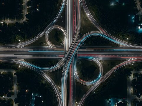 Aerial view of a complex highway interchange at night with light trails