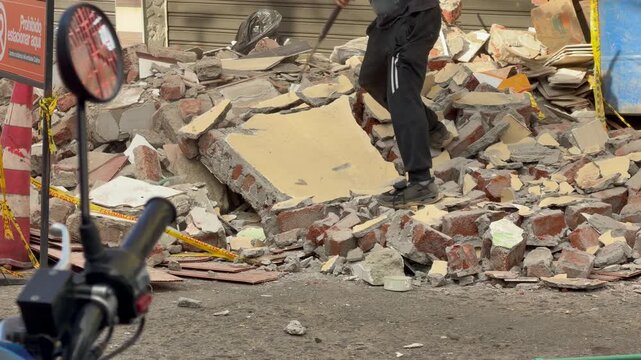 colombia earthquake cleanup worker clearing brick and concrete debris on street