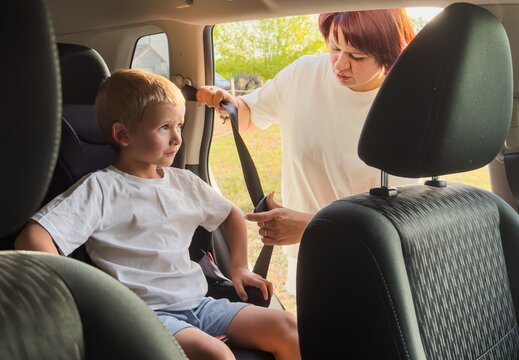 child being carefully strapped into car seat in car interior from passenger seat perspective with white and black materials and careful and attentive mood for family safety and parenting.