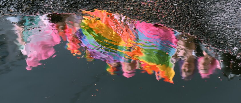 Rainbow-colored paint drips into a dark puddle