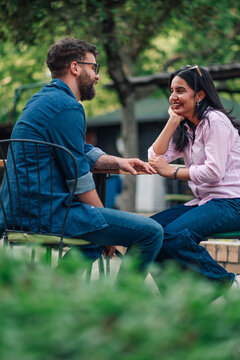 Diverse couple smiling, enjoying an engaging conversation at an outdoor cafe, sharing a moment of connection