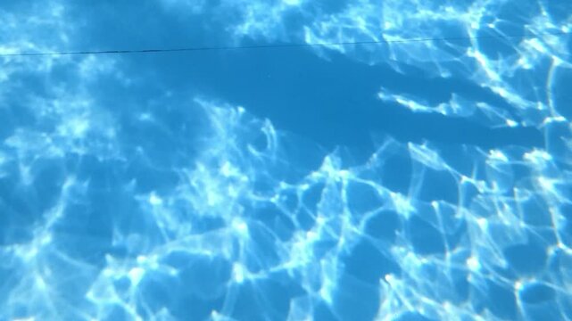 Sunlight shimmering on swimming pool water surface with ripples