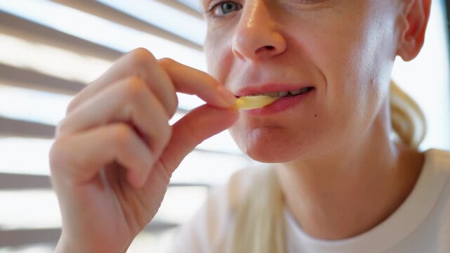 Close-up of hungry woman eating french fries in a fast food restaurant. Unhealthy meal, junk food, and overeating concepts, representing bad eating habits and appetite