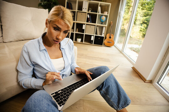 Woman working on laptop in cozy home office with natural light and stylish decor