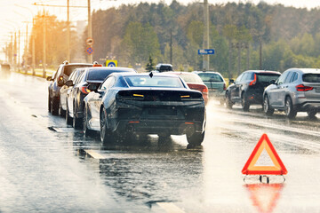 Naklejka na ściany i meble Multi vehicle car accident on wet highway during rain with red emergency warning triangle placed on road. Chain reaction car crash on wet highway during rainy weather. Major multi vehicle pile-up