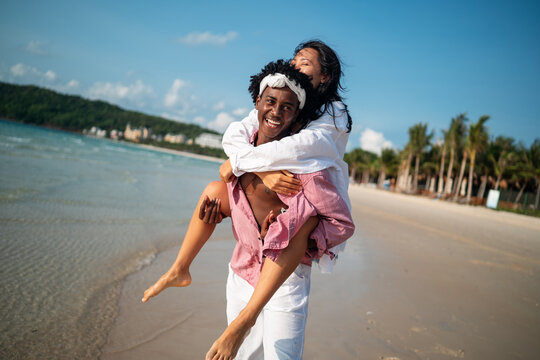 Happy young couple embracing and laughing on a tropical beach during summer vacation