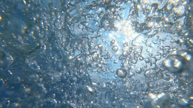 Water splashing and bubbling beneath pool surface with sunlight
