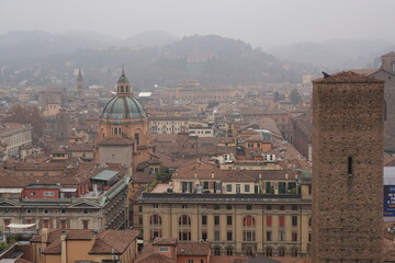 Aerial panoramic view of Bologna historic cityscape featuring the dome of San Bartolomeo church and Torre Asinelli against misty hills, Italy. © Alejandro Barchín