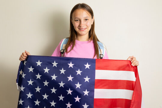 Teenage girl with backpack and American flag representing student exchange, studying abroad and international education