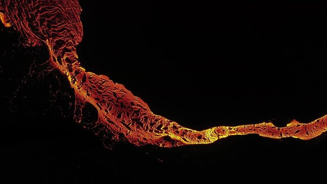 Volcanic eruption in Iceland 2023 at night. Lava flows in a channel and solidifies on a broad plain.