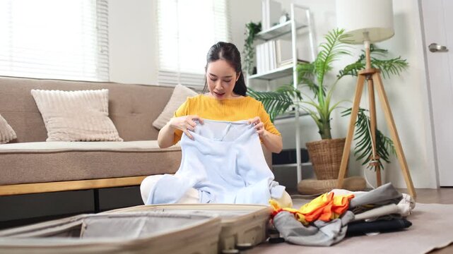 Woman packing clothes into suitcase for vacation travel at home