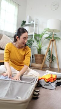 Woman packing clothes into suitcase for vacation travel at home