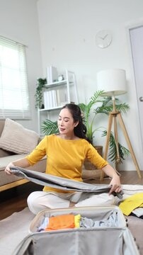 Woman packing clothes into suitcase for vacation travel at home