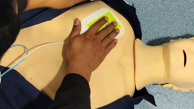 Medical students practicing CPR and defibrillator use on a mannequin